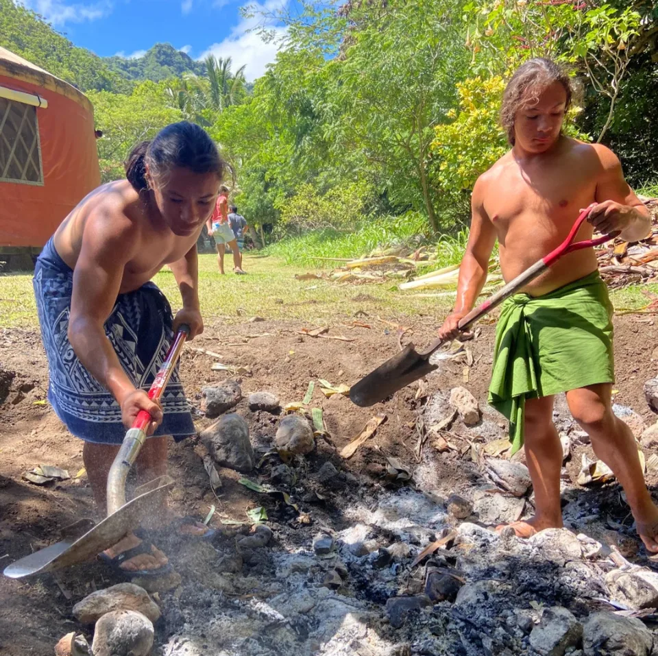 Two young people using shovels to work the ground outdoors.