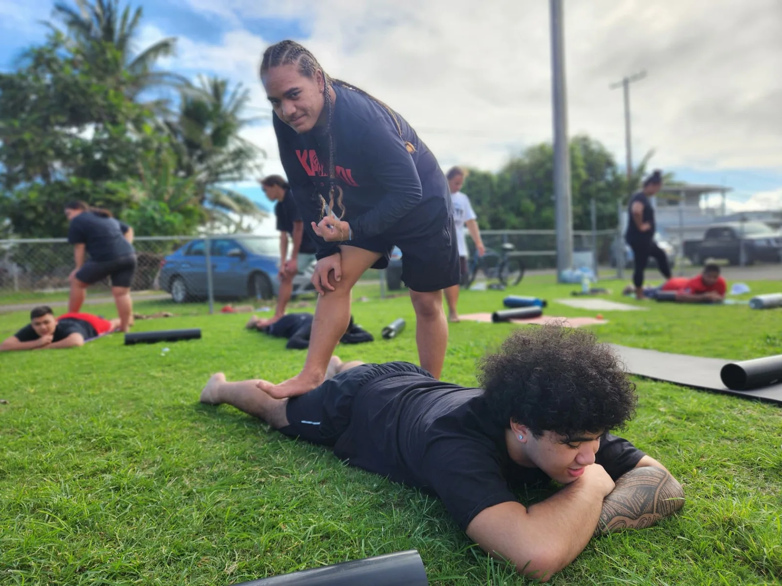 One participant assisting another with mobility work during an outdoor community session.