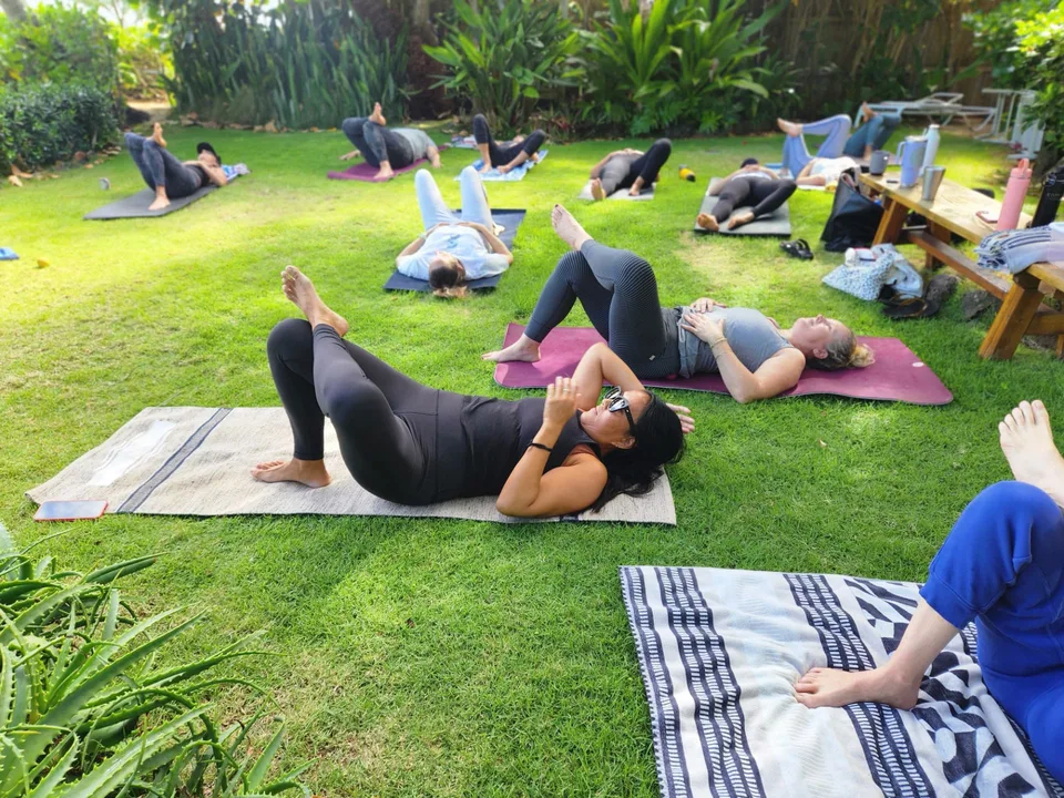 Adults practicing tension-release positions on mats outdoors.