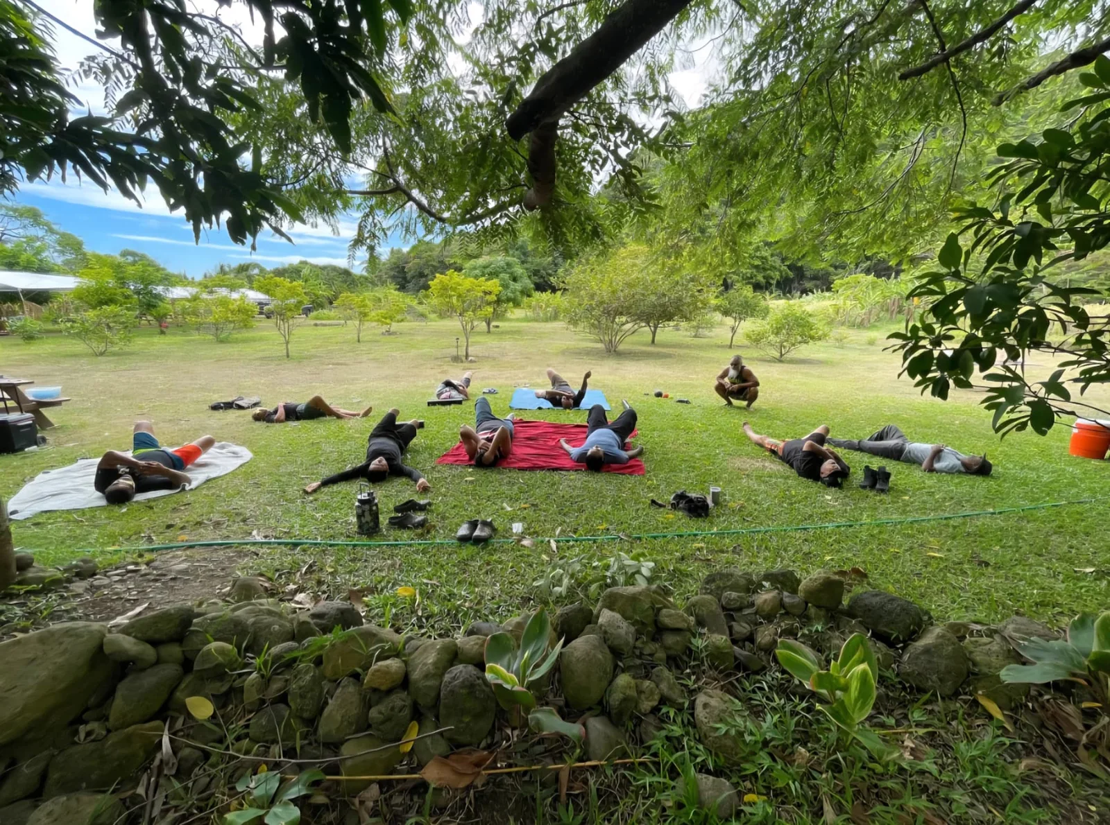 Men participating in an outdoor tension-release and self-care session during a community retreat.